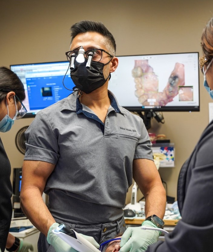 Dr. Advani performing implant surgery with surgical loupes